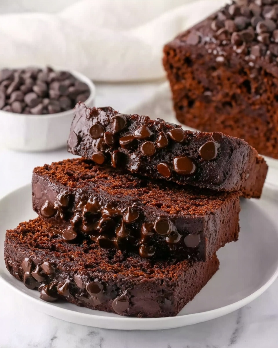 The image shows three slices of chocolate cake stacked on a white plate, with the top two slices topped with melted chocolate and sprinkled generously with chocolate chips. The cake texture looks moist and dense, with a rich dark brown color throughout. Next to the plate, there is a bowl filled with more chocolate chips. The background is a white marbled surface with a soft white cloth partially visible. Photo taken with an iphone --ar 4:5 --v 7