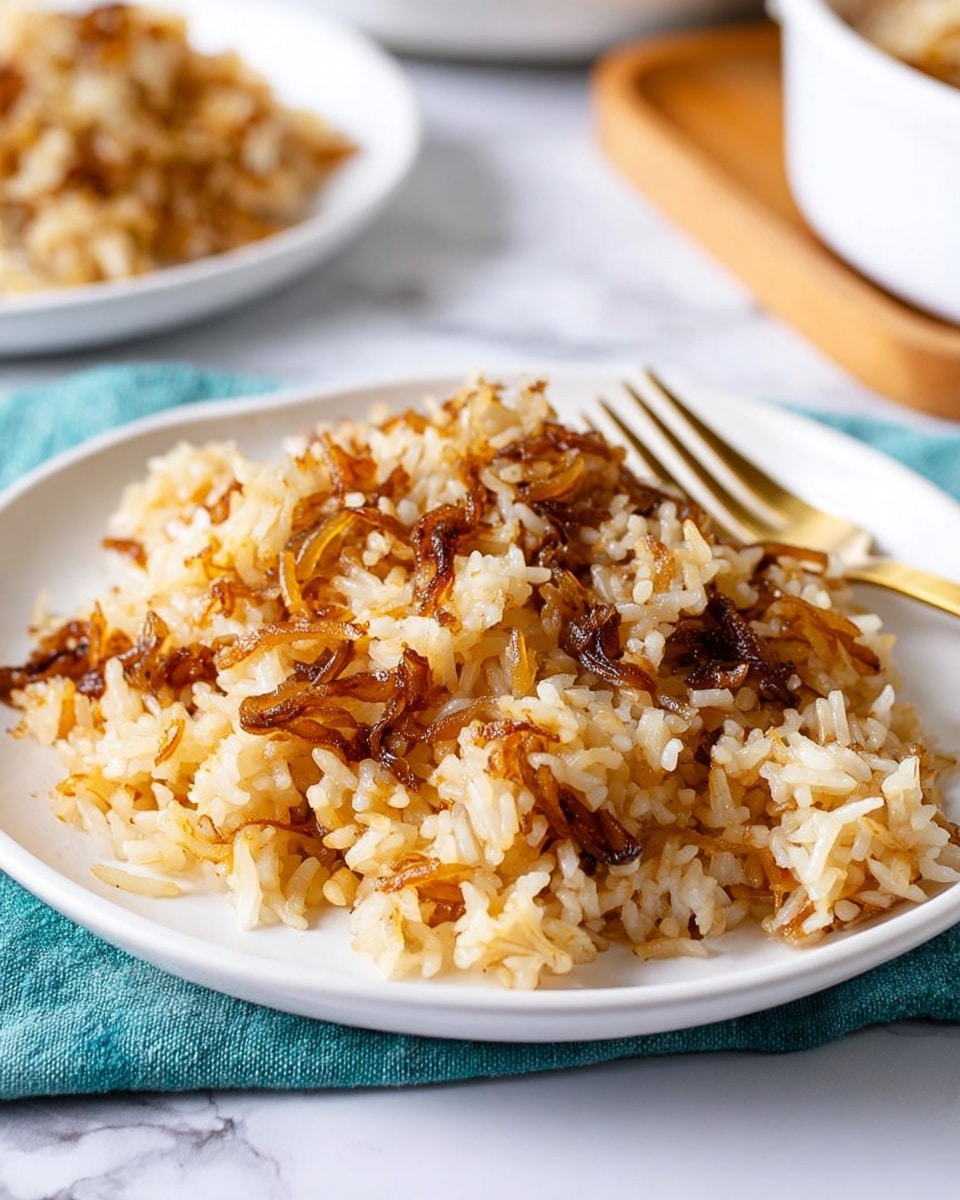 A white plate with a pile of cooked rice mixed with browned, caramelized onions scattered throughout, giving the dish a mix of light beige and golden brown colors with some darker browned bits on top. A gold fork rests diagonally behind the rice on the plate. The plate is set on a white marbled surface with a small part of a teal cloth visible at the front edge. In the blurry background, another white plate with a similar rice dish and a white container with a wooden tray can be seen. Photo taken with an iphone --ar 4:5 --v 7