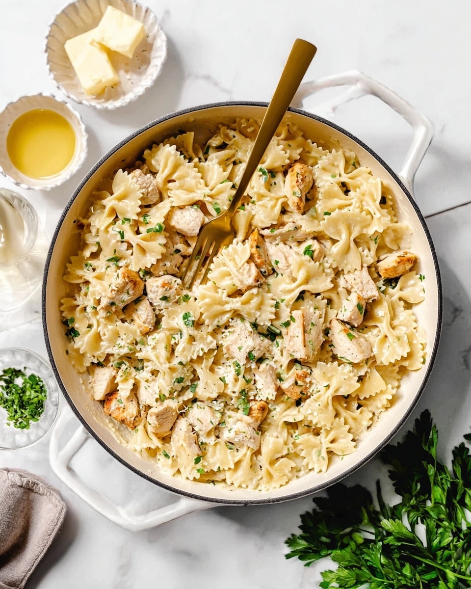 The image shows a white deep pan filled with bowtie pasta mixed with pieces of light golden cooked chicken scattered on top. The pasta is creamy and lightly coated, with small green herb bits spread throughout. A golden fork rests inside the pan, partly lifting some pasta. Around the pan, there are small white dishes holding butter cubes and a light yellow sauce, with a bunch of fresh green herbs on the white marbled surface. The lighting is bright, highlighting the creamy texture of the dish, photo taken with an iphone --ar 4:5 --v 7