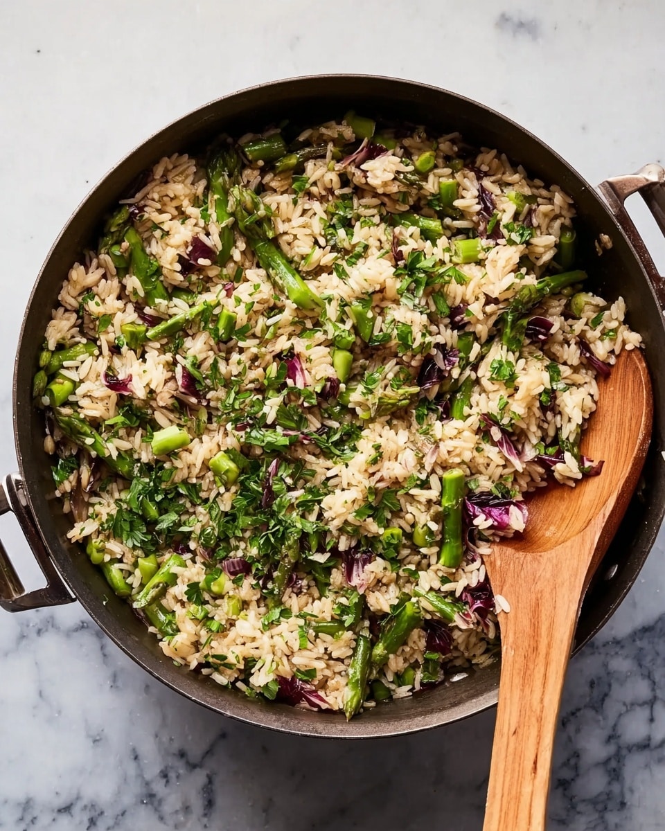 A large black pan filled with a mix of cooked rice, bright green asparagus pieces, and scattered purple-red leafy vegetables, likely radicchio, creating a colorful, textured blend. The rice grains are light brown and slightly glossy, layered evenly throughout the pan. Green parsley is sprinkled over the top, adding fresh green color. A wooden spoon with a smooth light brown finish lays inside the pan on the right side, partially submerged in the rice mixture. The pan rests on a white marbled surface with soft gray veins. photo taken with an iphone --ar 4:5 --v 7