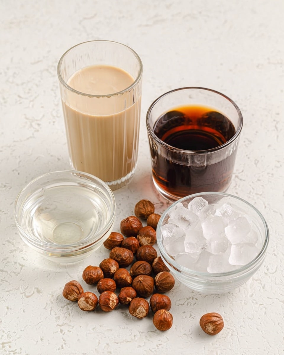 The image shows four clear glass containers arranged on a white marbled surface. On the left, a tall glass is filled halfway with a creamy light tan liquid. Next to it on the right is another tall glass holding a dark brown liquid. Below these two glasses is a small round bowl filled with a clear, almost colorless liquid. To its right is a medium-sized clear bowl filled with small, translucent white ice cubes. Scattered loosely across the front are many round, brown hazelnuts with a slightly rough texture. The setup is simple and clean, with items placed neatly to show the different textures and colors clearly photo taken with an iphone --ar 4:5 --v 7
