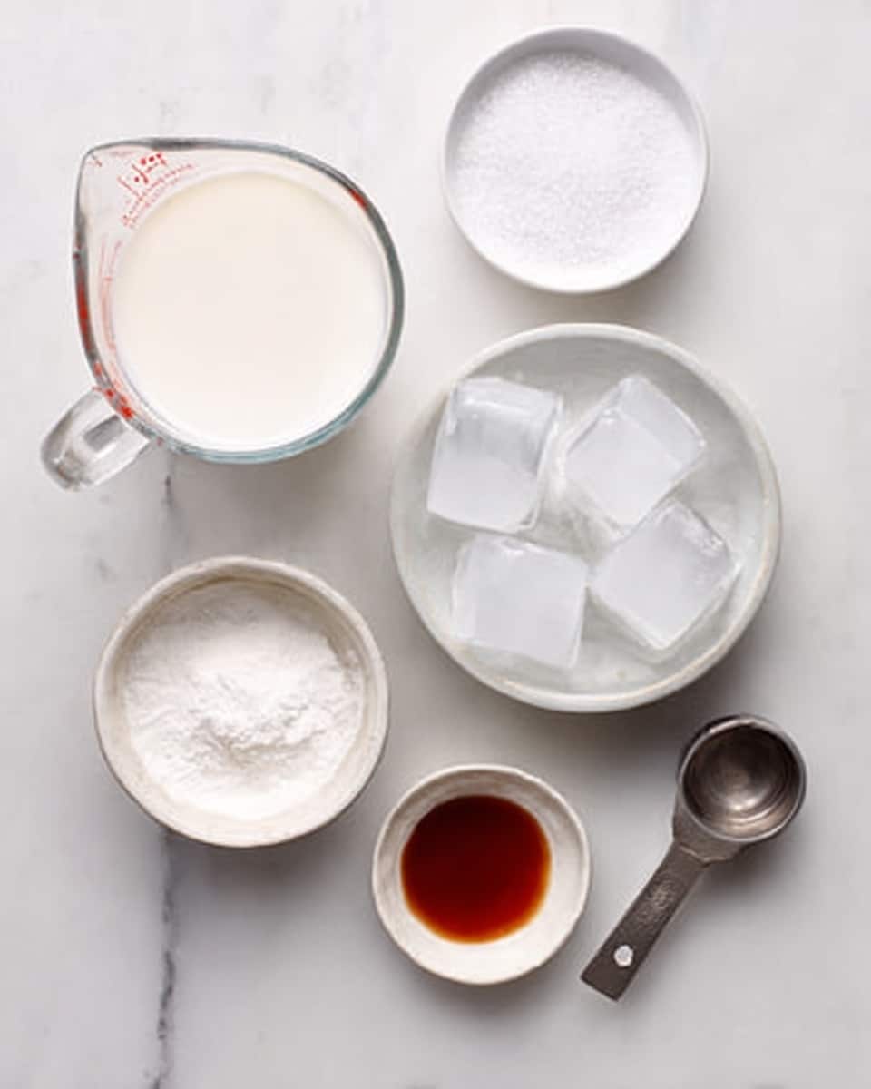 The image shows ingredients on a white marbled surface arranged neatly from top left to bottom right: a clear glass measuring cup filled with milk, a small white bowl with granulated sugar, a white bowl filled with large ice cubes, a metal measuring cup with white powder (likely flour or cornstarch), and a small white dish with dark amber liquid, possibly vanilla extract, all evenly spaced. photo taken with an iphone --ar 4:5 --v 7