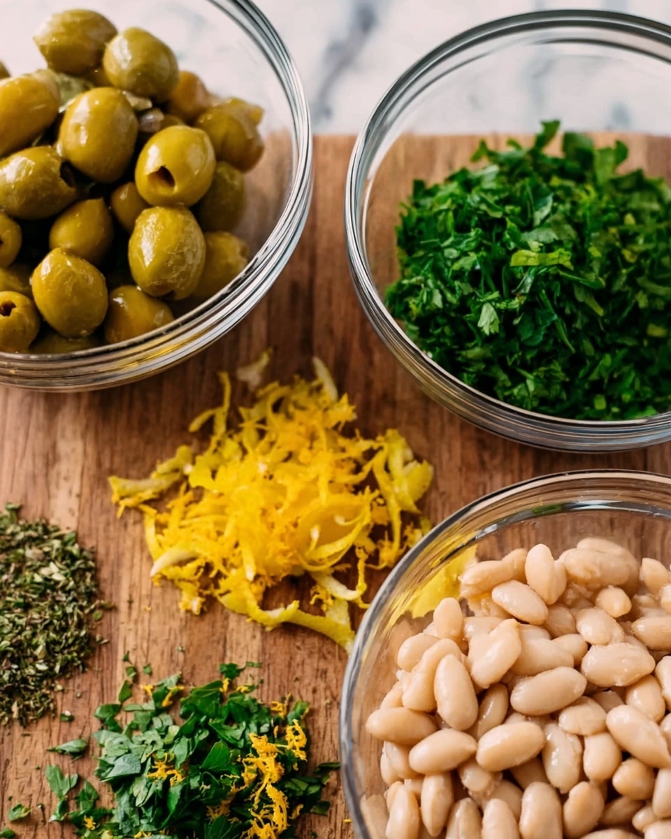 The image shows three clear glass bowls placed on a wooden surface with chopped fresh herbs and lemon zest directly on the table. The largest bowl in the front contains white beans with a smooth and soft texture. To the left, a medium bowl holds whole green olives with a shiny and firm look. Above all, on the wooden surface, there are bright yellow lemon zest shavings spread next to finely chopped green herbs that look fresh and leafy. The background surface is white marbled texture. photo taken with an iphone --ar 4:5 --v 7
