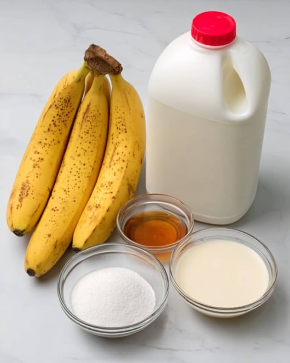 The image shows a white marbled surface with ingredients neatly arranged. There is a large white plastic gallon of milk with a red cap on the right side. Next to it are three ripe yellow bananas with small brown spots lying close together. In front of the bananas, there are three clear glass bowls; one filled with white granulated sugar, another with a light brown liquid syrup, and the last with a smooth, creamy white liquid. The overall setup is clean and simple. photo taken with an iphone --ar 4:5 --v 7