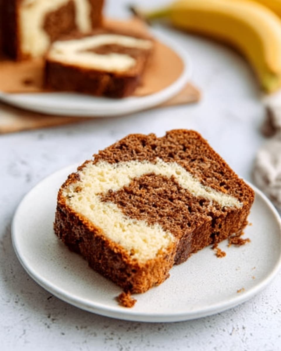 The image shows a white plate on a white marbled surface with a slice of marble cake on it. The cake has two visible layers: a brown layer with a rough, crumbly texture and a creamy light beige swirl running through the center. The edges are slightly uneven and a bite is taken out of the slice on the plate. In the background, there is another white plate with a full slice of the same cake, and part of a banana is visible on the right side. Photo taken with an iphone --ar 4:5 --v 7