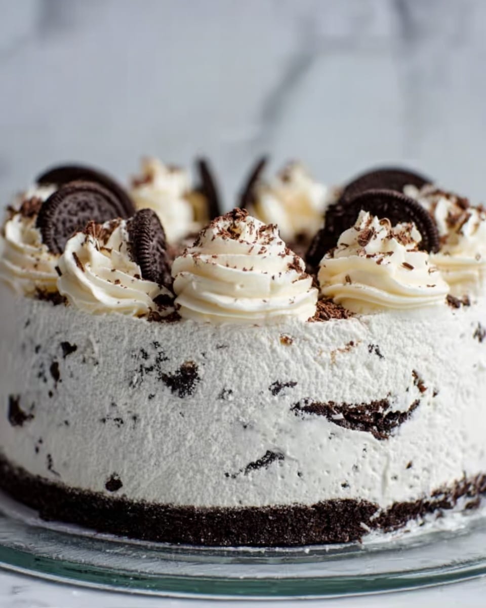 The image shows a round cake with several visible layers, starting with a base layer of dark chocolate cookies at the bottom. Above the cookie layer is a thick layer of white cream with a rough texture and some small chocolate crumbs mixed in. The cream layer is thick enough to cover the cookies but has small gaps where the dark cookies show through. On top of the cake, there are swirls of whipped cream with chocolate flakes sprinkled on them. The cake sits on a clear glass plate, and the background has a white marbled texture. Photo taken with an iphone --ar 4:5 --v 7
