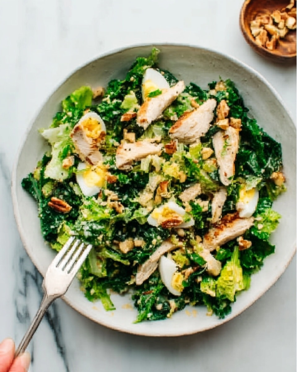 A white bowl filled with a fresh green salad sits on a white marbled surface. The salad has several layers: the base is made of dark leafy greens, topped with pieces of light brown grilled chicken strips scattered evenly. There are small chunks of yellow boiled egg mixed throughout, along with some toasted nuts adding a crunchy texture. Tiny bits of a creamy light-colored dressing are spread lightly over the top. A silver fork is placed inside the bowl with a woman's hand about to grab a bite. Photo taken with an iphone --ar 4:5 --v 7