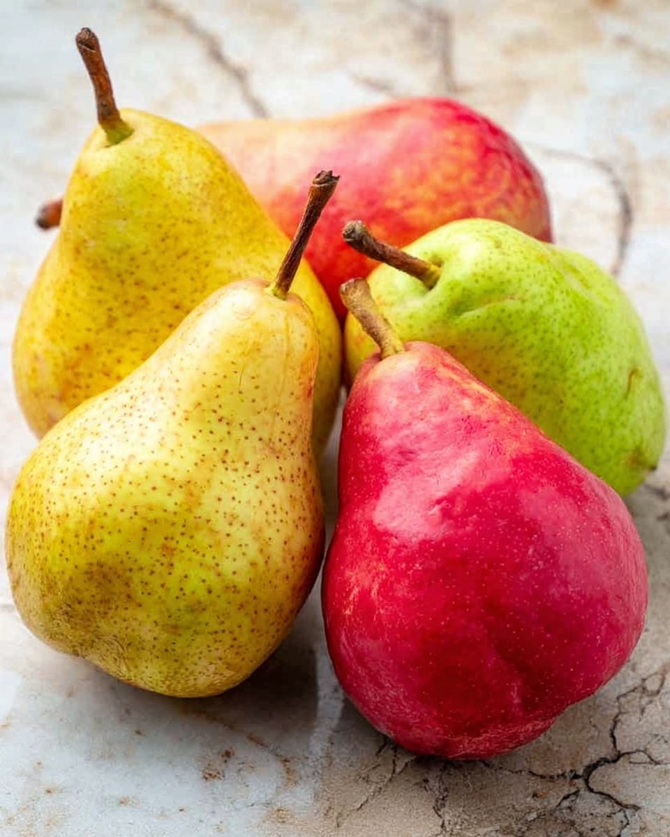 The image shows a small group of pears placed closely together on a white marbled surface. There are five pears in total, with three in the front and two slightly behind them. The pears have different colors: two are a soft yellow with small brown spots and two are a bright red color, while one in the back is a pale greenish-yellow. Each pear has a brown stem at the top. The surface beneath them has visible natural cracks and textures, adding a rustic contrast to the smooth skins of the pears. photo taken with an iphone --ar 4:5 --v 7