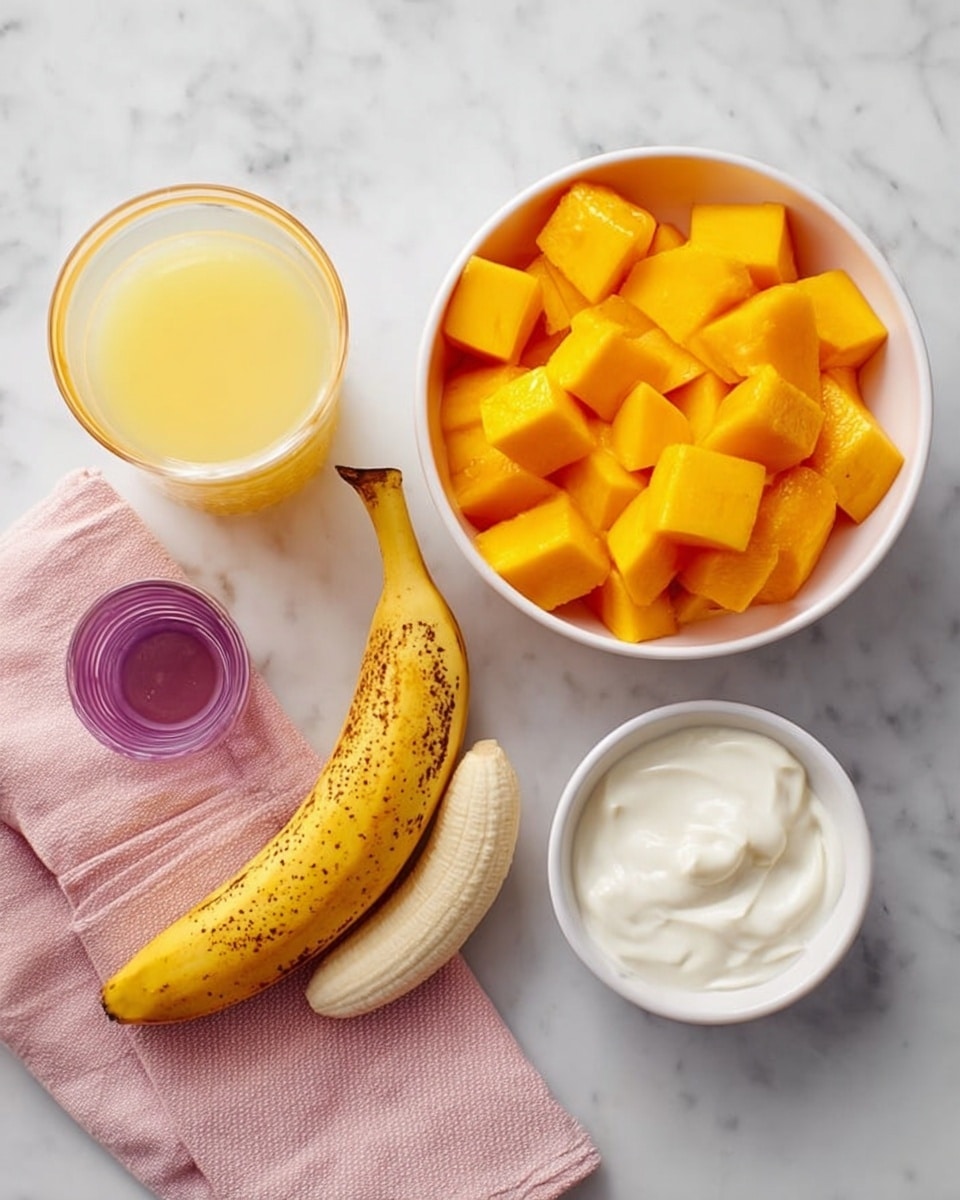 The image shows a white bowl filled with bright orange mango cubes on the right side. Above it, a smaller white bowl contains thick white yogurt. In the center, a small white dish holds a peeled yellow banana with a brown spot on its skin, split into two sections. To the left, there is a clear glass cup filled with light yellow juice, and below it, a small round purple container with golden honey inside. A soft pink cloth is folded beside the glass on a white marbled surface. photo taken with an iphone --ar 4:5 --v 7