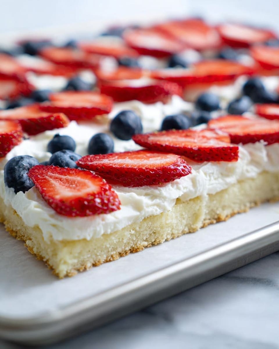 The image shows a close-up view of a rectangular fruit tart with three layers. The bottom layer is a light golden crust with a soft, crumbly texture. The middle layer is thick and white, made of smooth whipped cream spread evenly across the crust. The top layer consists of thin slices of red strawberries arranged in rows, with whole blue blueberries placed in between some of the strawberry slices. The tart is on a baking sheet lined with parchment paper, set on a white marbled surface. photo taken with an iphone --ar 4:5 --v 7