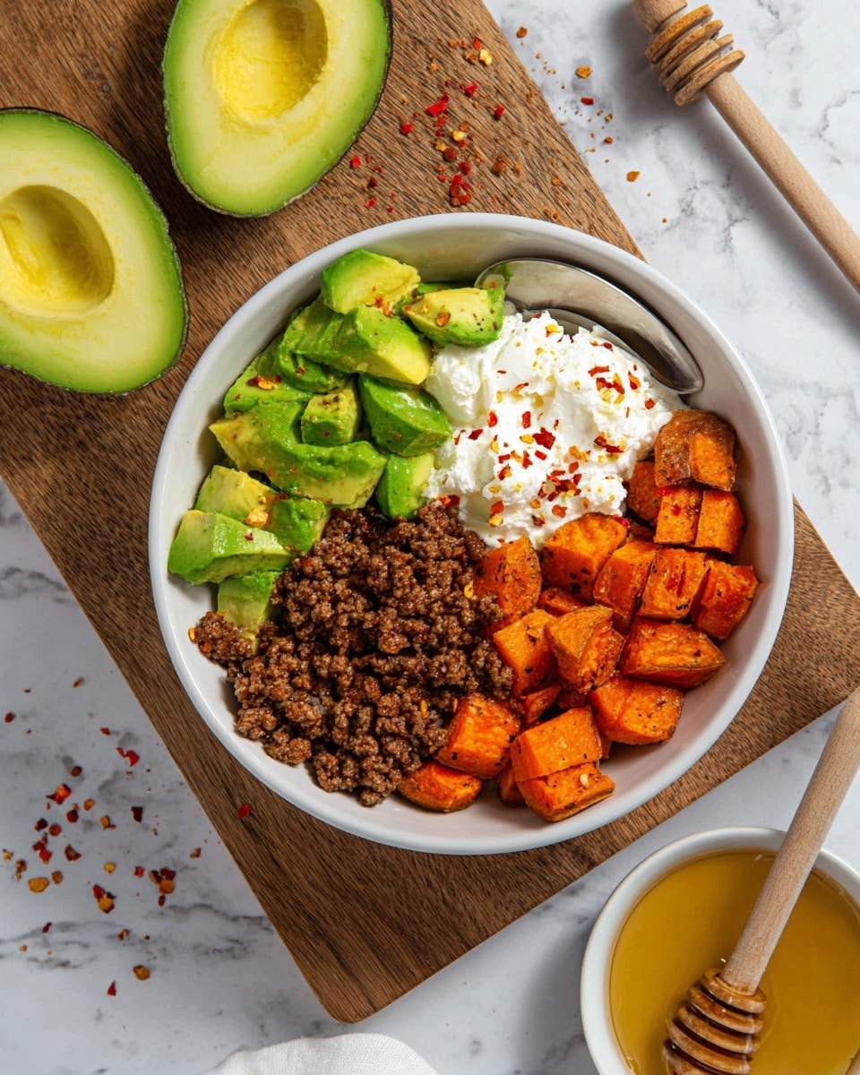 A white bowl is divided into four sections with different foods: bright green chunks of avocado with smooth texture on the top left, a pile of cooked brown ground meat with a crumbly texture on the bottom left, a spoonful of white cottage cheese topped with red chili flakes on the top right, and roasted orange sweet potato cubes with a slightly rough surface on the bottom right. The bowl sits on a wooden board with red chili flakes scattered around, and two halves of a green avocado with creamy light green flesh and a large seed are placed next to it on a white marbled surface. In the lower right corner, a small white bowl filled with golden honey has a wooden honey dipper resting in it. Photo taken with an iphone --ar 4:5 --v 7