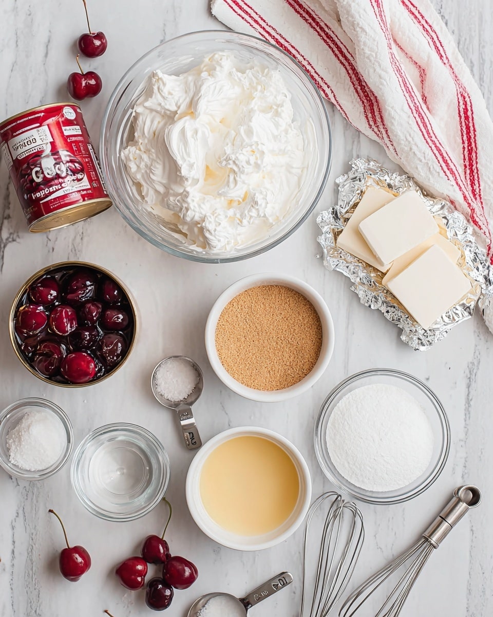 The image shows an arrangement of baking ingredients on a white marbled surface. There is a clear glass bowl filled with fluffy white whipped cream near the center top, a pack of cream cheese on the right side with its foil partially open showing white cream cheese blocks. To the left of the whipped cream is an open can filled with dark red cherries in syrup. Below the can is a small white bowl filled with light brown fine crumbs, likely graham cracker crumbs. At the bottom center is a white bowl with a pale yellow liquid, and a round metal measuring cup filled with white powdered sugar is to its left. There are small glass bowls with clear and white liquids along with a wooden spoon labeled