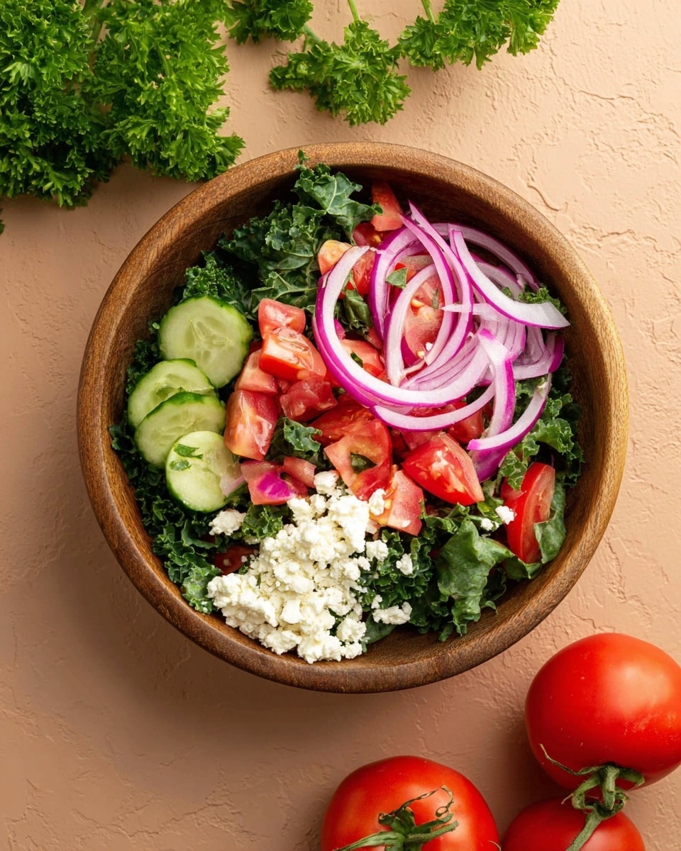 A wooden bowl filled with fresh green kale as the base layer, topped with bright red tomato pieces and green cucumber slices mixed together, with thin slices of purple-red onions placed on top, and a small pile of white crumbly cheese sitting on one side. The bowl is placed on a smooth light brown surface, with green parsley leaves in the upper left corner and a cluster of red tomatoes with green stems in the lower right corner. photo taken with an iphone --ar 4:5 --v 7
