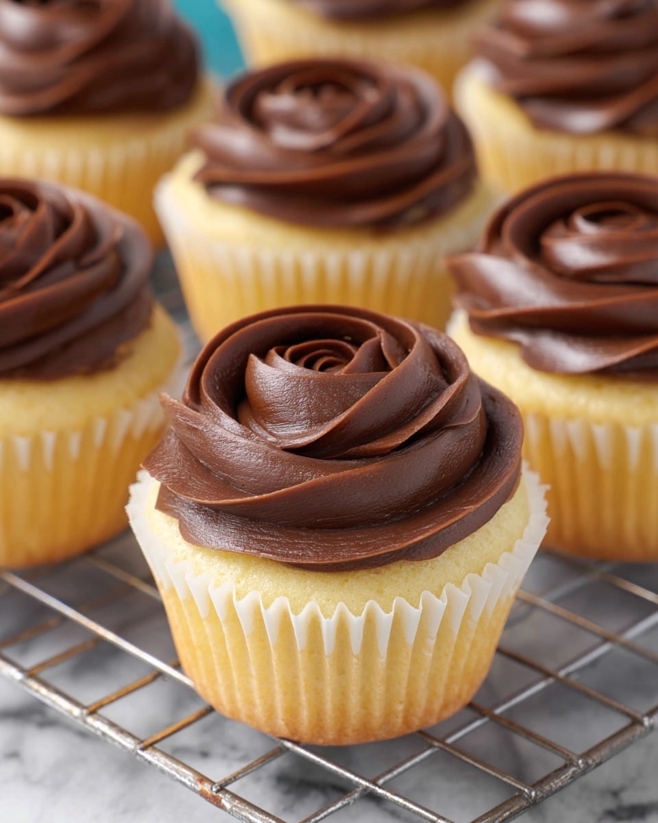 Seven cupcakes are placed on a round black cooling rack over a white marbled surface with a blue and white patterned cloth underneath. Each cupcake has a light golden base with a thick swirl of smooth, dark brown chocolate frosting on top, shaped like a rose. To the top left side, there is a stack of white plates with wooden forks on them and a blue napkin. At the top right, there is a small white bowl filled with dark chocolate chips, with some chips scattered on the cloth, and beside it, a small glass bottle of milk with a blue and white striped straw. Photo taken with an iphone --ar 4:5 --v 7