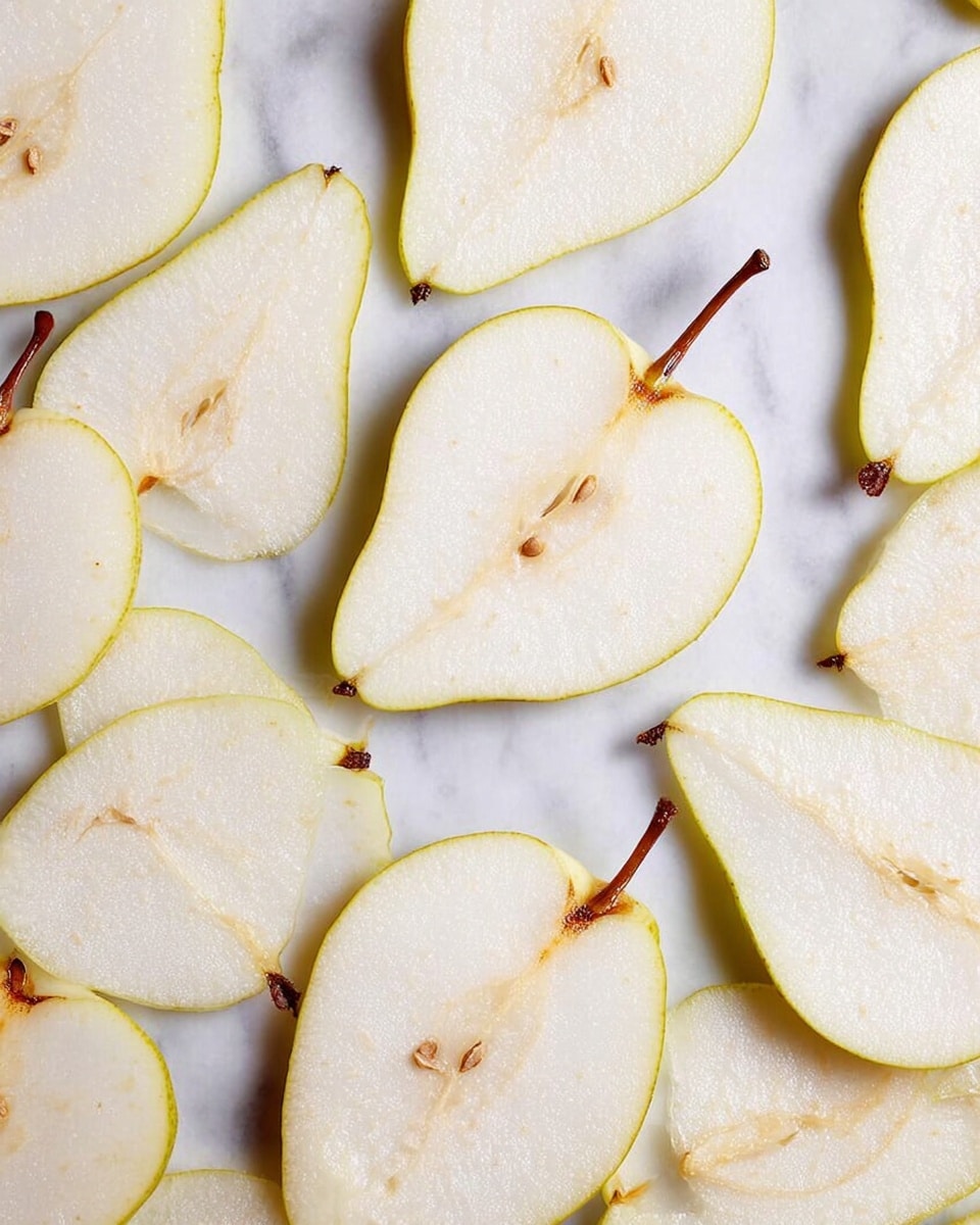 Thin slices of pear are spread out flat in an even layer, each slice showing its light cream flesh with a thin yellow skin edge. Some slices have visible small brown seeds in the center, and one slice includes a short brown stem. The slices lie on a surface with a white marbled texture, arranged in close but not overlapping positions, filling the frame evenly. photo taken with an iphone --ar 4:5 --v 7