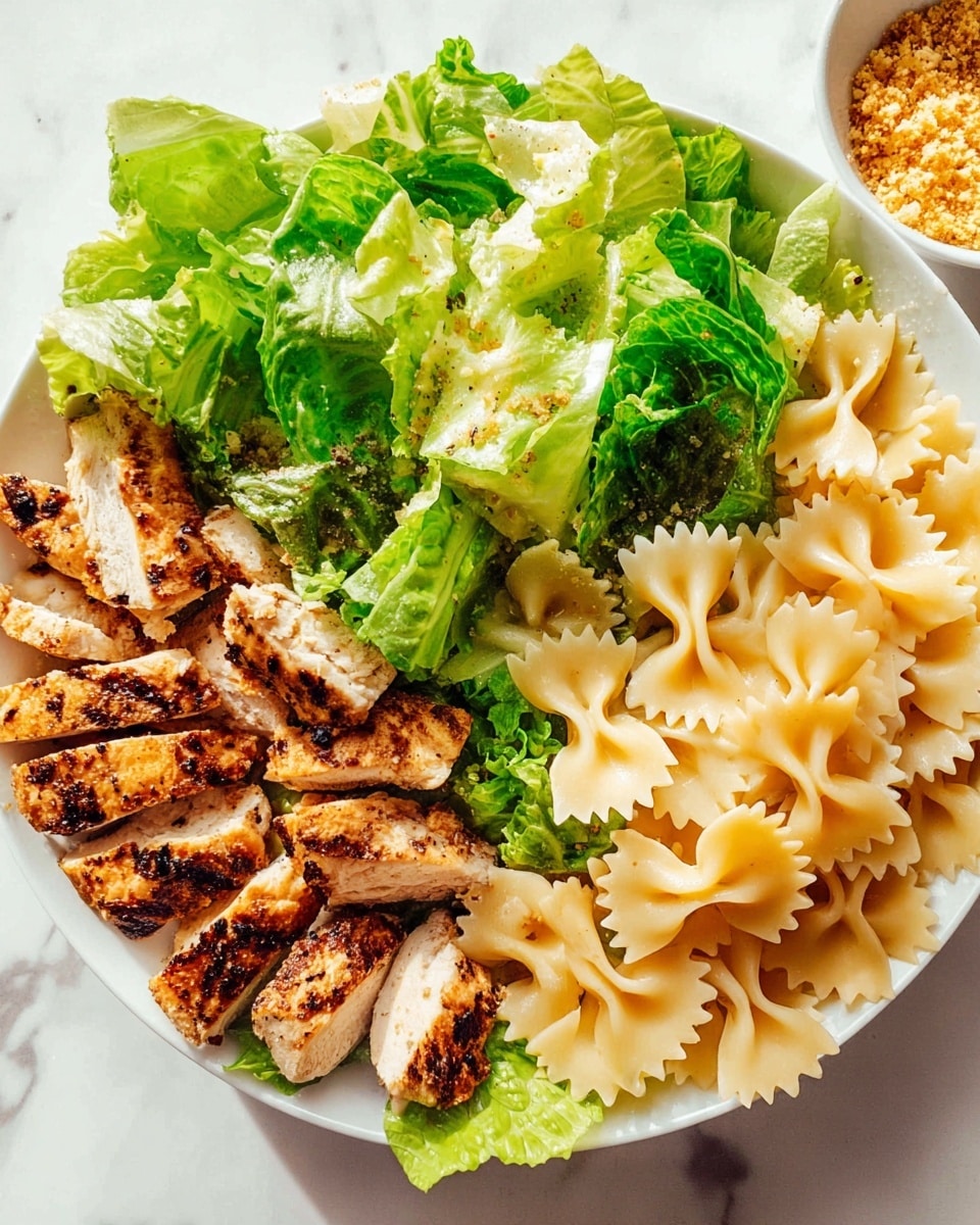 A white plate with three sections: on the left, grilled chicken pieces with a browned, slightly charred texture cut into strips; in the middle, fresh green leafy lettuce with a mix of light and dark green shades; on the right, pale yellow bowtie pasta with a smooth texture and ruffled edges. The plate is placed on a white marbled surface, and there is a small bowl with a golden breadcrumb topping partially visible at the top right corner. Photo taken with an iphone --ar 4:5 --v 7