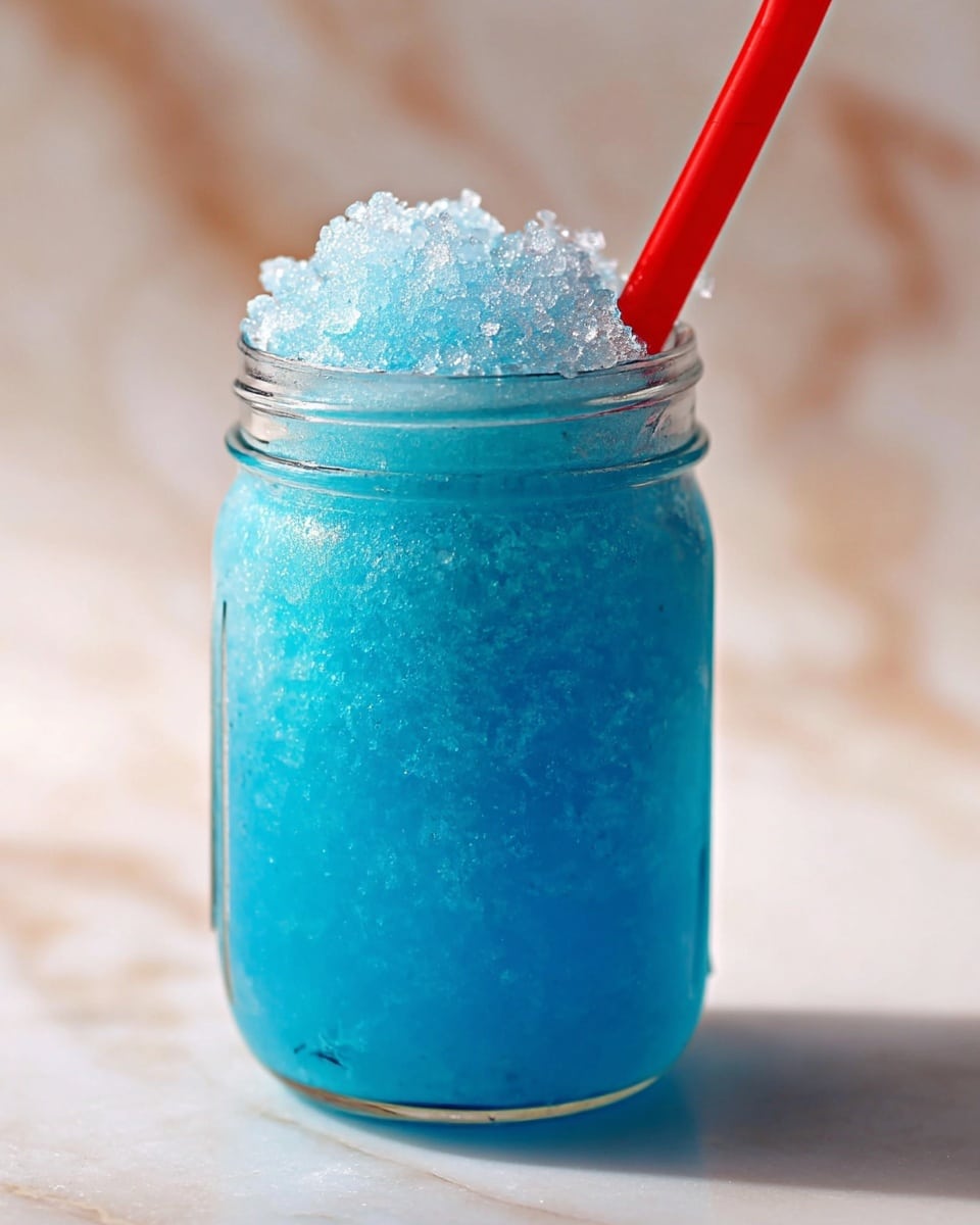 A clear glass jar filled with a bright blue icy drink with a crushed ice layer on top, showing a rough, translucent texture. A thick red straw is placed in the middle, partly buried in the blue crushed ice. The jar is set on a white marbled surface with a soft focus on the background. photo taken with an iphone --ar 4:5 --v 7