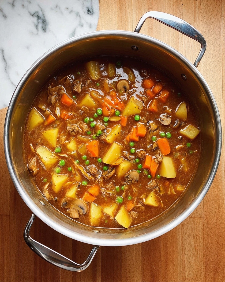 A large silver pot filled with a thick brown stew showing chunks of orange carrots, light yellow potatoes, pale celery, green peas, small brown pieces of meat, and sliced beige mushrooms all mixed in a rich brown sauce. The pot handles are wide and metallic, and the pot is placed on a surface with a white marbled texture. photo taken with an iphone --ar 4:5 --v 7