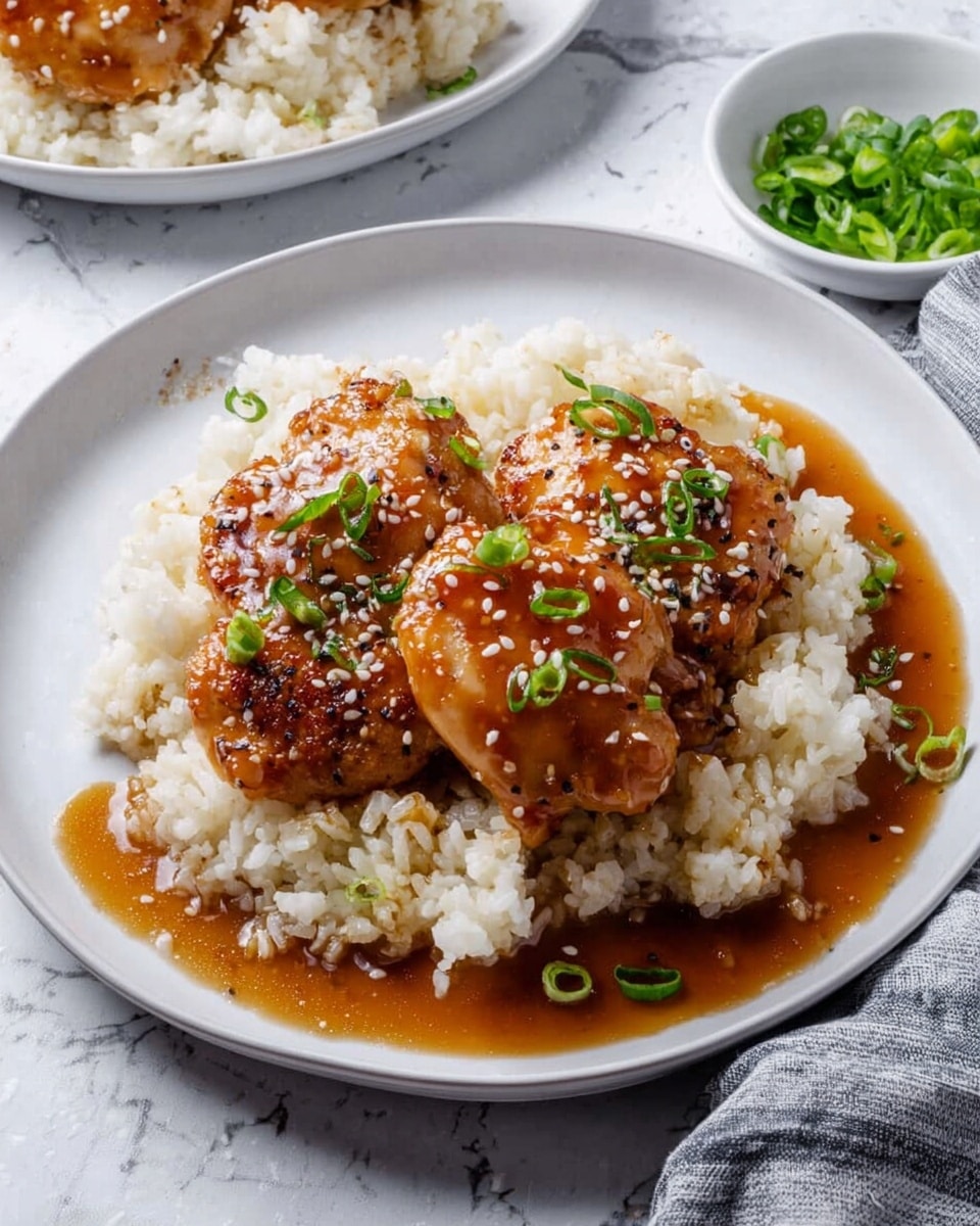 A white plate holds a bed of soft, white rice with two caramel-colored glazed chicken pieces on top, covered in a shiny brown sauce. The chicken is garnished with small green onion slices and sprinkled with white sesame seeds. Around the rice, the sauce pools slightly, adding a rich texture. The background shows a white marbled surface with another similar plate partially visible and a small white bowl filled with green onions nearby. photo taken with an iphone --ar 4:5 --v 7