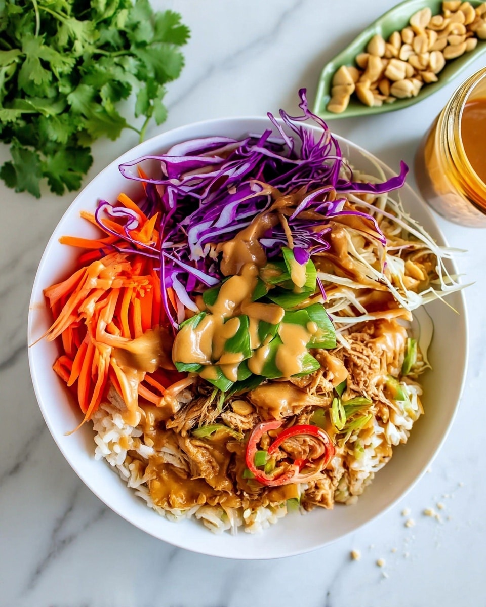 A white bowl filled with layers starting from the bottom with light brown rice, topped with shredded light brown chicken mixed with red chili slices and green chopped scallions on one side. Next to it, there are thin strips of bright orange carrots, followed by thinly sliced purple cabbage strands, and shredded white cabbage along the edge. In the center, there are green chopped bell peppers, all covered with a smooth, light brown peanut sauce drizzled evenly over the top. Around the bowl, there is a small white marbled surface with scattered crushed peanuts, a small green dish of whole peanuts, fresh green cilantro, and a partially visible glass jar of peanut sauce. A woman's hand with a silver spoon rests near the bowl on a turquoise cloth. photo taken with an iphone --ar 4:5 --v 7