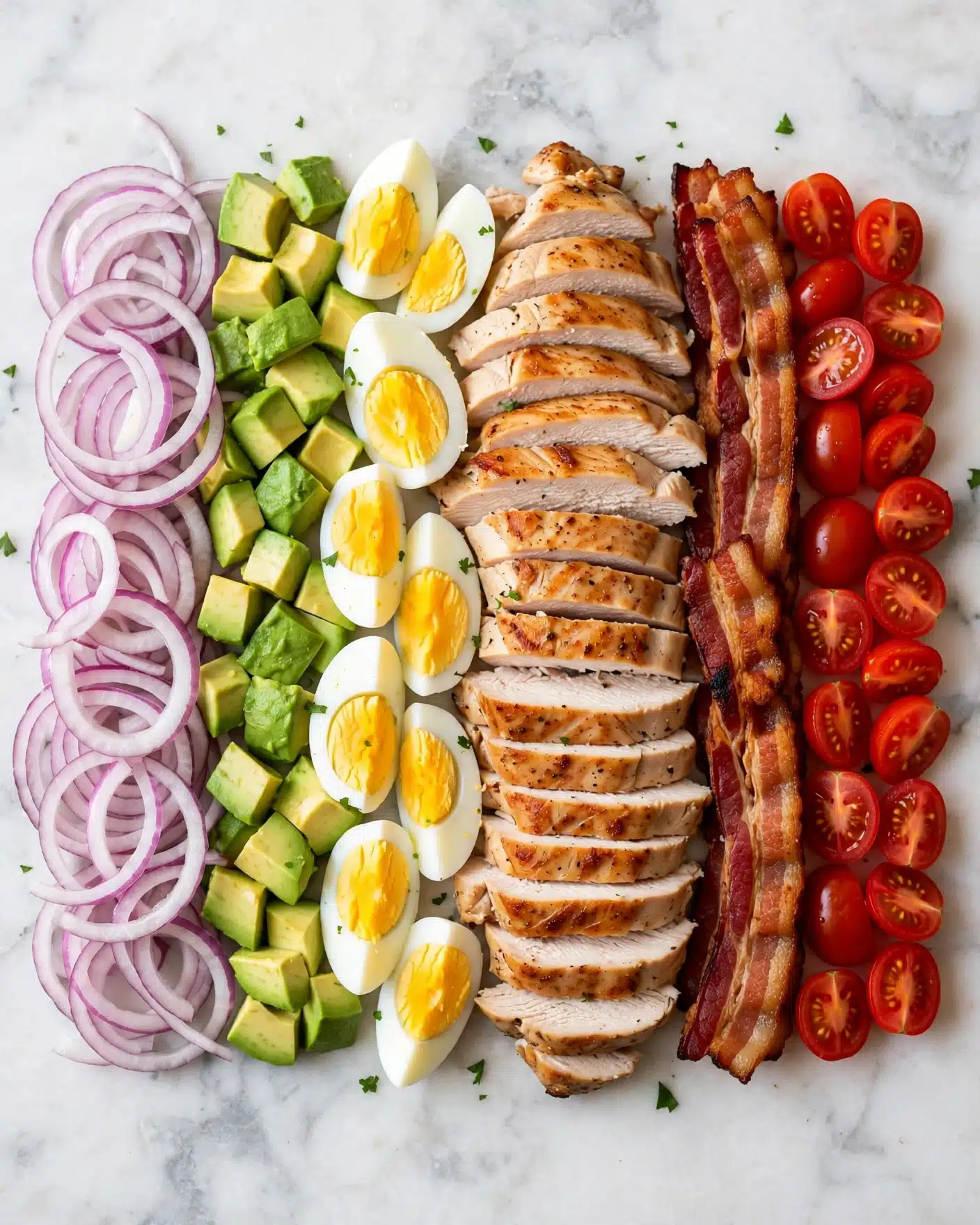 This dish is a colorful layered salad arranged neatly on a white marbled surface. Starting from the left, there is a layer of thinly sliced red onions with a crisp texture and light purple color. Next to it, there is a layer of diced green avocado pieces. Beside the avocado, there are quartered hard-boiled eggs with white outer layers and yellow yolks in the center. Moving right, there is a large layer of sliced, cooked chicken with a light brown crust and white inside, stacked in strips. To the right of the chicken, there is a strip of crispy brown bacon with some reddish hues. The final layer on the right is bright red cherry tomatoes that are halved showing their juicy inside. The overall look is fresh, vibrant, and neatly arranged. Photo taken with an iphone --ar 4:5 --v 7