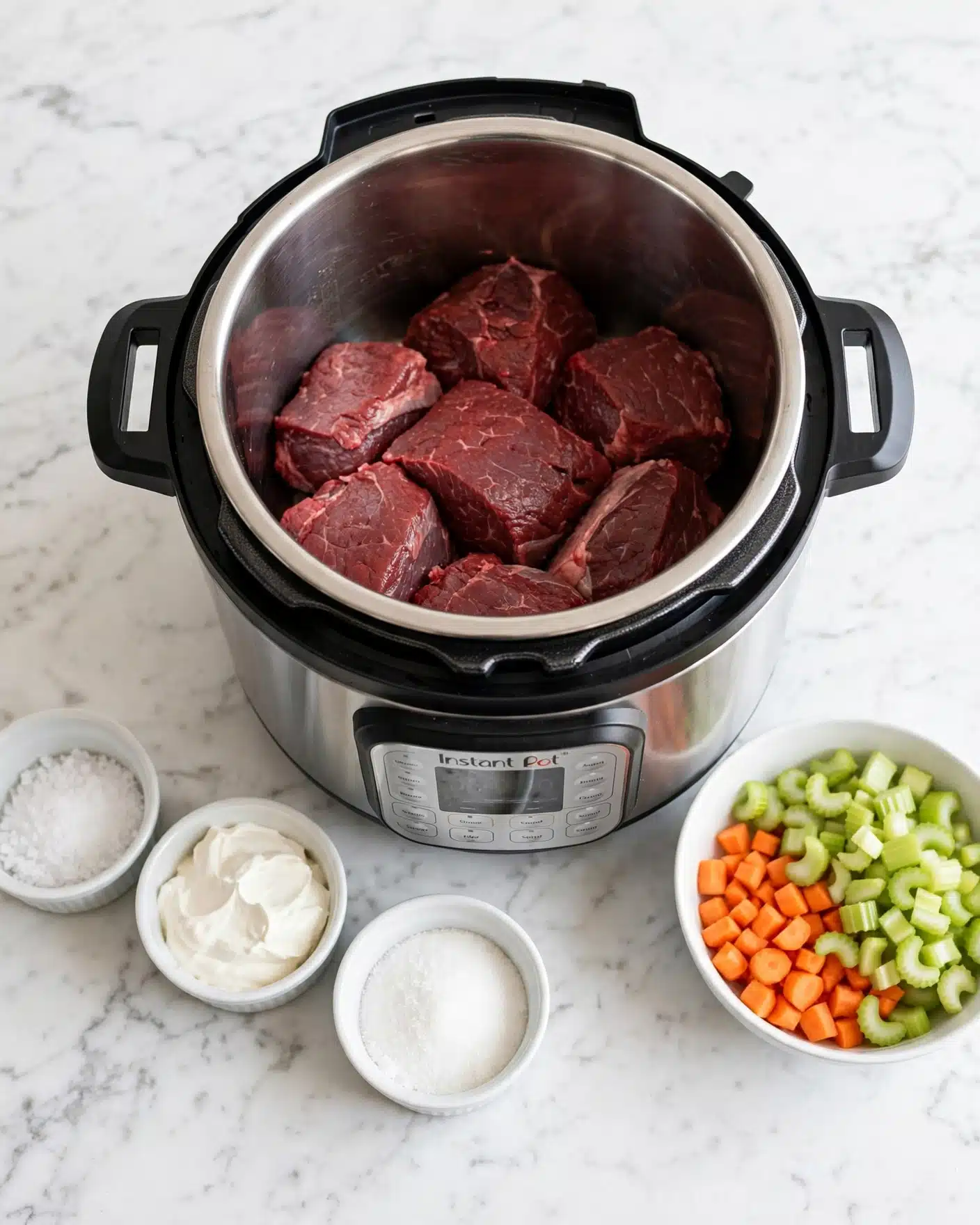 Life Changing Instant Pot Beef Stew Recipe 4 The image shows an Instant Pot filled with several dark red chunks of raw beef in the center. To the right, there is a white bowl with pieces of chopped carrots and light green celery. On the left side, three small white bowls contain white coarse salt, white sour cream, and white granulated sugar. All items are set on a white marbled surface, and the scene is brightly lit with a clean and simple look photo taken with an iphone --ar 4:5 --v 7