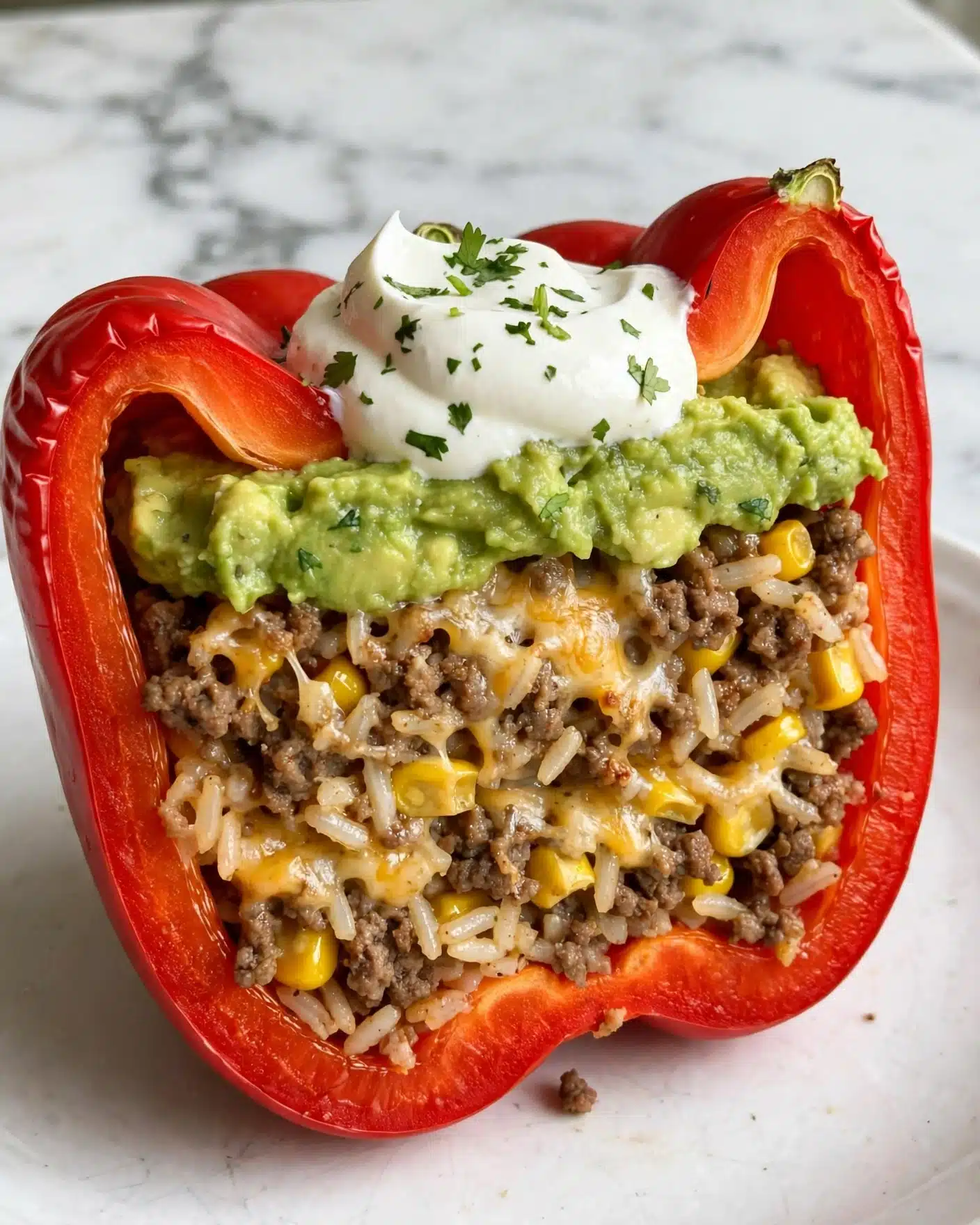The image shows a close-up of a stuffed red bell pepper half, filled with a mix of cooked ground meat, melted cheese, and yellow corn kernels, giving it a rich brown and yellow color texture on top. The pepper has bright red skin with a slightly wrinkled texture visible on the edges. The filling looks moist and chunky, with small bits of green herbs scattered inside. A silver fork is gently resting in the stuffed pepper, positioned on a white plate that has a smooth surface with a few small garnish pieces around the food. The background is a rustic light brown wooden texture, adding warmth to the scene. Photo taken with an iphone --ar 4:5 --v 7